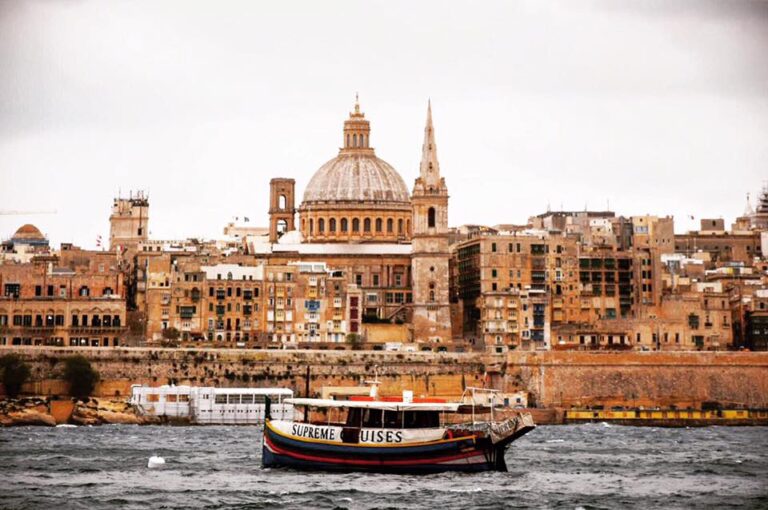 Landscape view of Valletta, Malta with the sea and a traditional boat in front