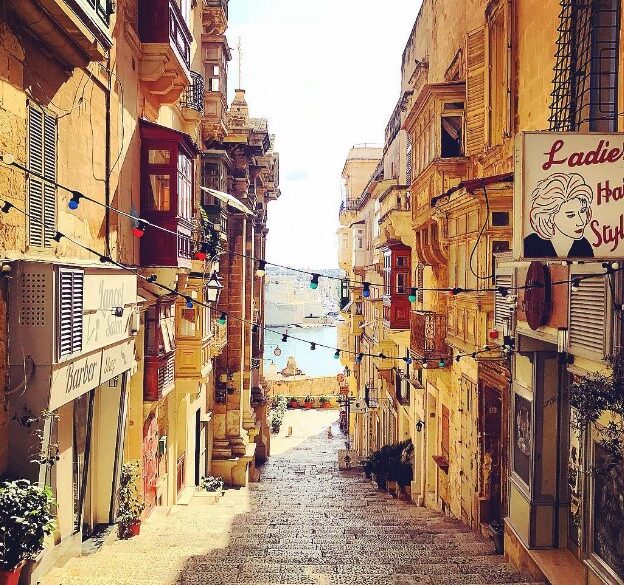 A narrow street in Valetta leading to the sea with Mediterranean style houses on both sides