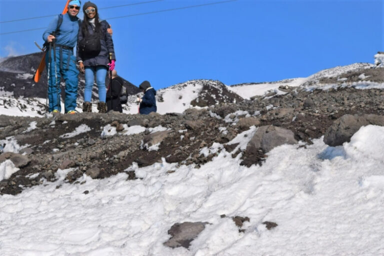 A man and a woman posing on a mountain top covered in snow. Winter on Mt. Etna, a low-budget winter destination in Italy