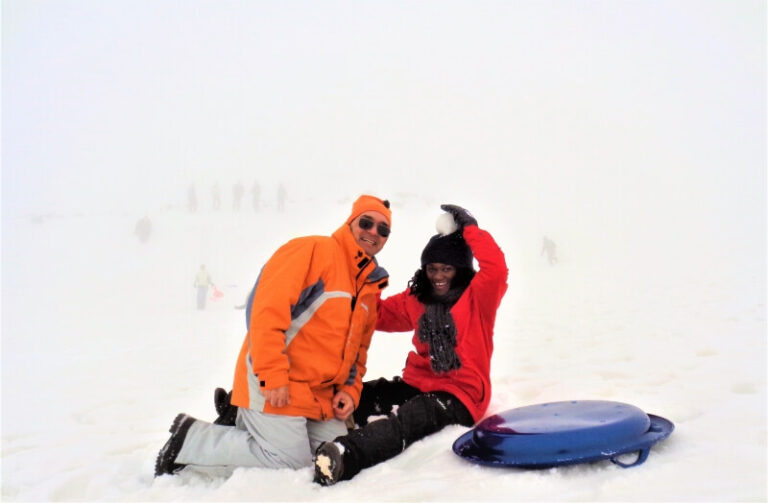 A couple on the ground surrounded by snow on Mt. Etna, a low-budget winter destination in Italy
