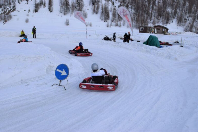 A winter scene of a race track for ski karting with drivers on the track in Livigno, a low-budget winter destination in Italy
