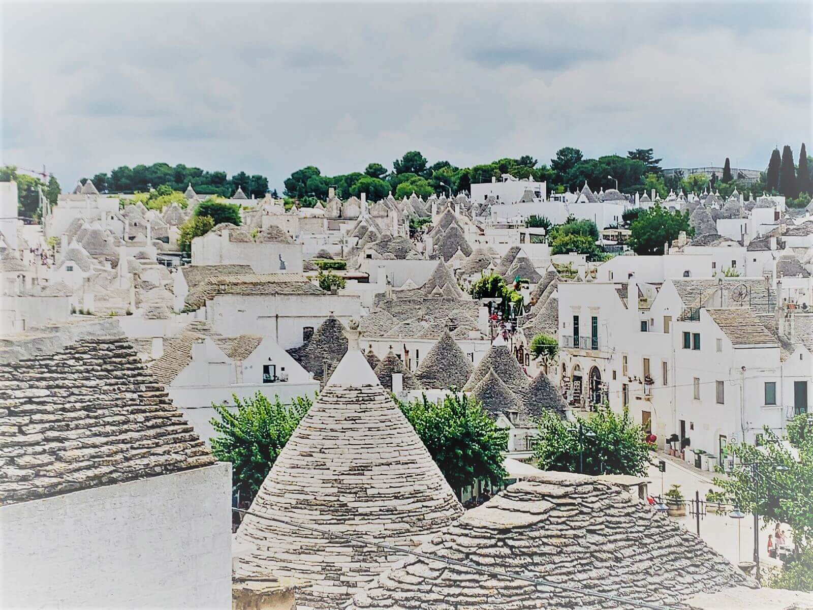 A scene of a town with white round houses and conical roofs known as Trulli