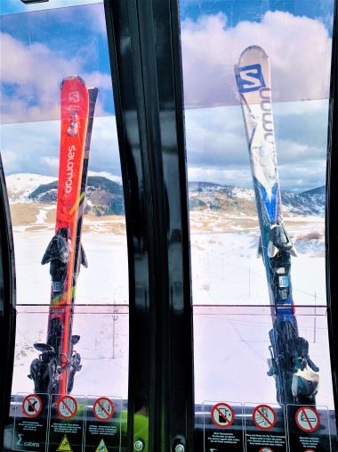 Two sets of skis in a ski cabin with the view of the mountains outside in Roccaraso, a low-budget winter destination in Italy