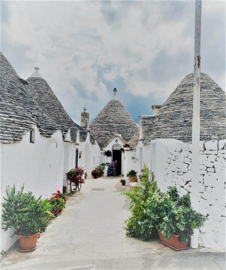A whitewashed narrow street with conical white houses and plants
