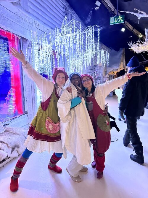 3 women posing for a picture. the two women on either sides are dressed as elves