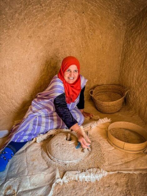 A woman in a mud room sitting on the floor and spinning a mill wheel in Matmata, Tunisia
