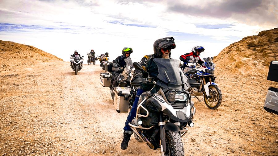 A group of motorcyclists riding in a v-formation on a desert landscape